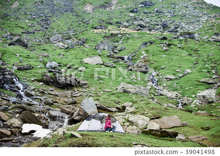 Girl in tent on rocky slope  39041498