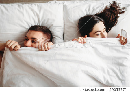 Shy love couple lies on big white bed, top view 39055771