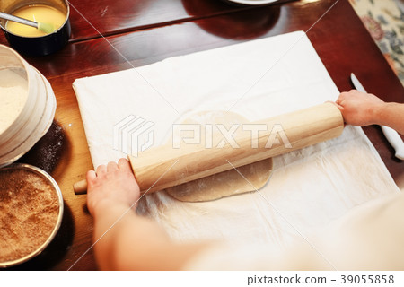 Chef roll out the dough with rolling pin, top view 39055858