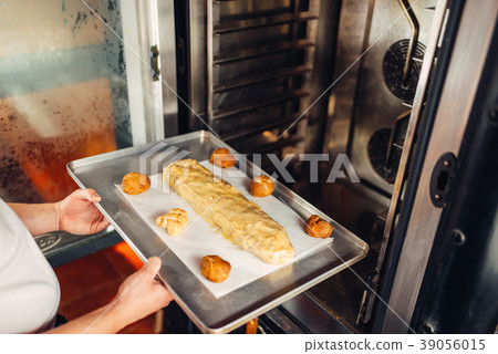 Chef puts strudel on baking sheet in the oven Chef puts strudel on baking sheet in the oven 39056015