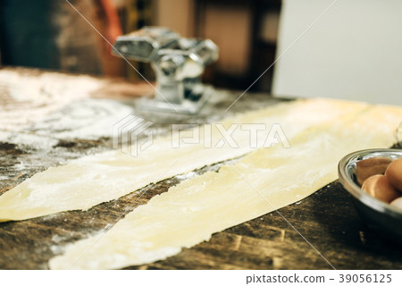 Pasta machine, dough and eggs on kitchen table Pasta machine, dough and eggs on kitchen table 39056125