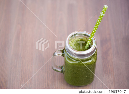 A green smoothie in a mason jar with tube  39057047