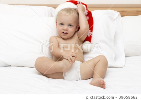 Baby with santa hat sitting on a white sofa 39059662