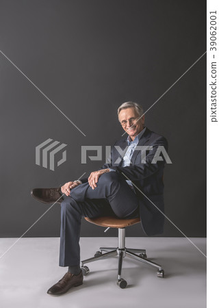 Cheerful old businessman relaxing on cozy chair 39062001
