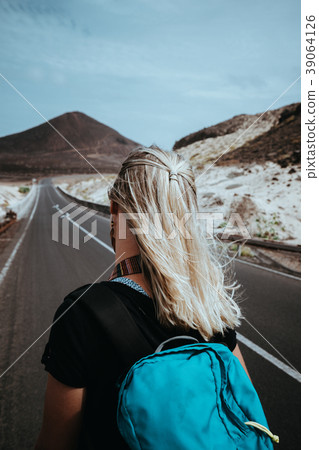 Woman traveler goes on desolate straight road over 39064126