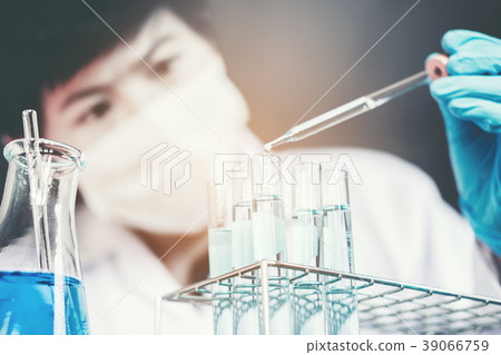 Scientist dropping chemical liquid to flask in lab 39066759