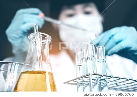 Scientist dropping chemical liquid to flask in lab 39066760