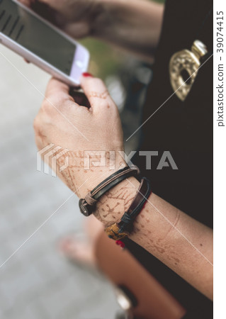 Mehndi tattoo and leather strip on the womans hand Mehndi tattoo and leather strip on the womans hand 39074415