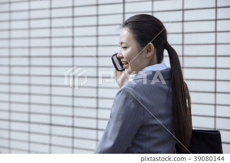 A young business woman who uses a smartphone outdoors A young business woman who uses a smartphone outdoors 39080144