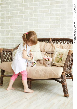 Little sweet girl. Cozy sofa. Light background 39082564