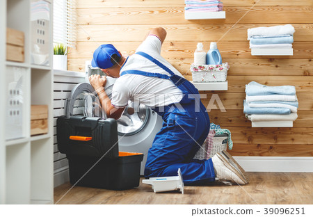 working man plumber repairs washing machine in laundry. working man plumber repairs washing machine in laundry. 39096251