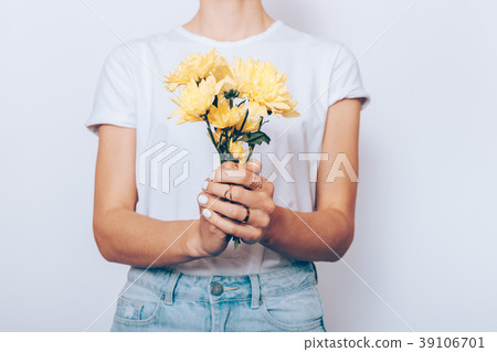 Woman in a T-shirt and jeans holds flowers Woman in a T-shirt and jeans holds flowers 39106701