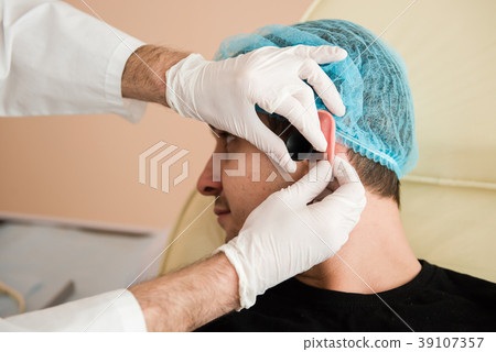 Otolaryngologist hands check patient ear Otolaryngologist hands check patient ear 39107357