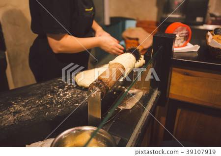 The hands of a female baker cook trdelnik or Trdlo The hands of a female baker cook trdelnik or Trdlo 39107919