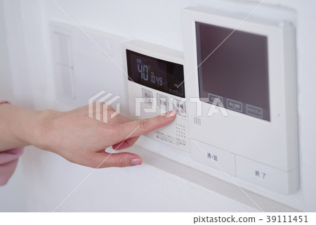 Woman operating hot water remote control in kitchen 39111451
