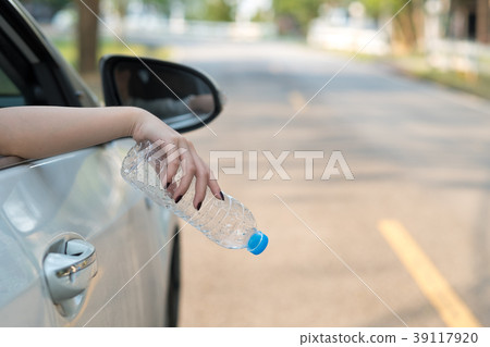 Hand throwing plastic bottle on the road 39117920
