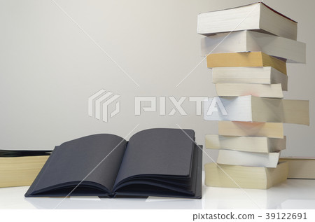 Black open book in foreground of pile of books Black open book in foreground of pile of books 39122691