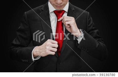 Businessman in black suit tying red necktie 39130780