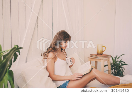 Young woman at home sitting on bed and relaxing Young woman at home sitting on bed and relaxing 39141480