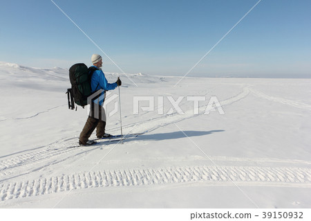 Man with a backpack is skiing on on a snowy river Man with a backpack is skiing on on a snowy river 39150932