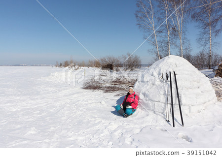 Happy woman skier sitting near an igloo Happy woman skier sitting near an igloo 39151042