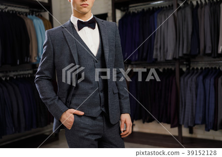 young man in classic vest against row of suits in young man in classic vest against row of suits in 39152128