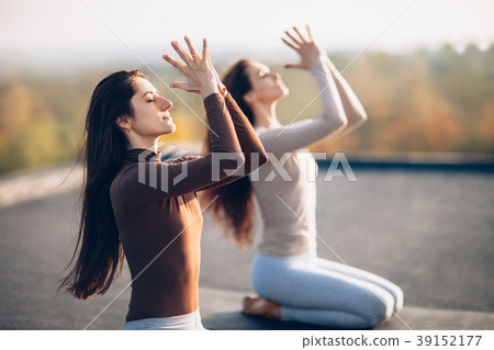 Two young beautiful women doing yoga asana on the roof outdoor Two young beautiful women doing yoga asana on the roof outdoor 39152177