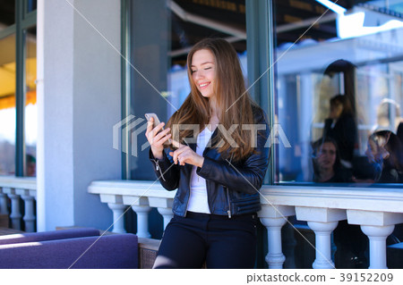 Young woman typing by smartphone at street cafe. Young woman typing by smartphone at street cafe. 39152209