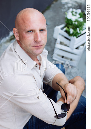 Bald handsome man sit on the flowers background, n 39154413