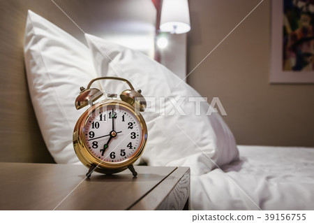 alarm clock stands on a bedside table 39156755