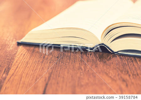Opened old hard cover book on wooden table Opened old hard cover book on wooden table 39158784