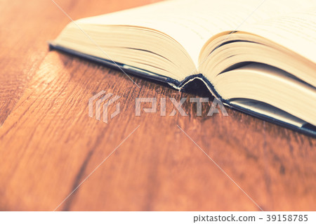 Opened old hard cover book on wooden table Opened old hard cover book on wooden table 39158785