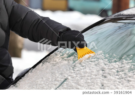 Winter scene, driver cleaning windshield of car 39161904