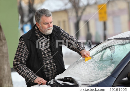 Winter scene, driver cleaning windshield of car 39161905