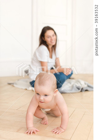 Woman watching baby crawling on floor Woman watching baby crawling on floor 39163532