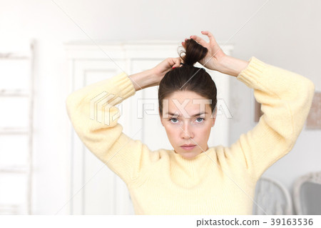 Casual woman making hairstyle looking at camera Casual woman making hairstyle looking at camera 39163536