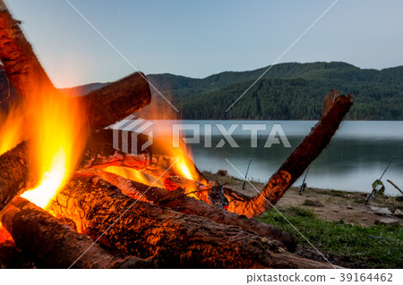 Slowly burning fire at lake shore 39164462