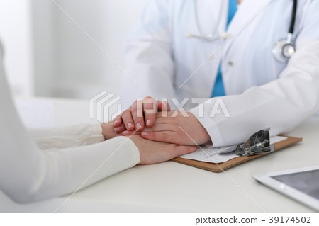 Medicine doctor hand reassuring her female patient Medicine doctor hand reassuring her female patient 39174502