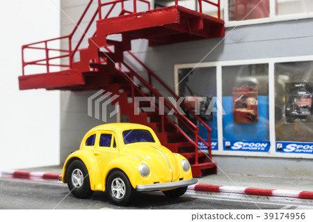 Yellow toy car parking in front of custom car shop Yellow toy car parking in front of custom car shop 39174956