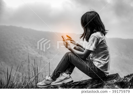 Asian woman sitting on the rock at smart phone Asian woman sitting on the rock at smart phone 39175979