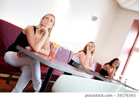Three women waiting in restaurant looking sideway 39176363