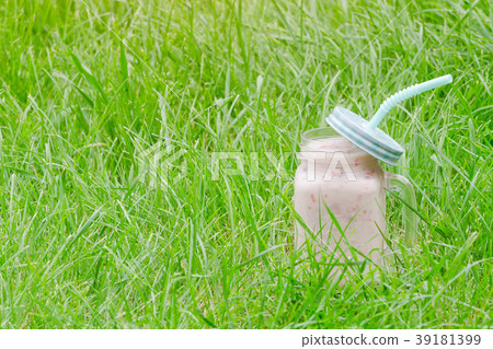 Mug of yogurt on a background of green grass 39181399