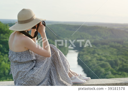 Side view of a girl with a camera. View from hill Side view of a girl with a camera. View from hill 39181578