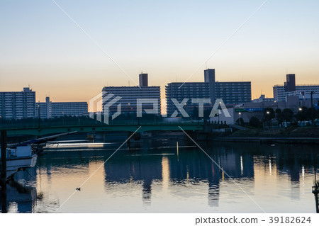 在日出和建築物的高層公寓樓反映在水面 在日出和建築物的高層公寓樓反映在水面 39182624