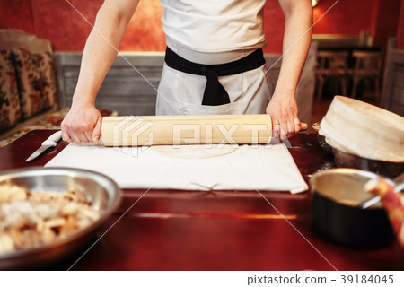 Male chef roll out the dough with a rolling pin 39184045