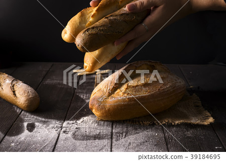 Close-up of woman hands take fresh bread. Dark 39184695