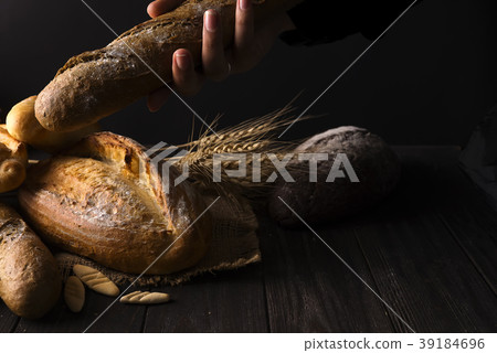 Close-up of woman hands take fresh bread. Dark 39184696