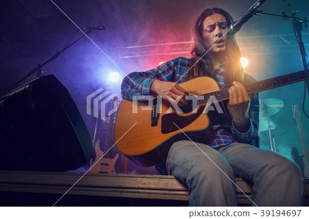 The musician plays an acoustic guitar. Scene 39194697