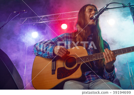 The musician plays an acoustic guitar. Scene 39194699