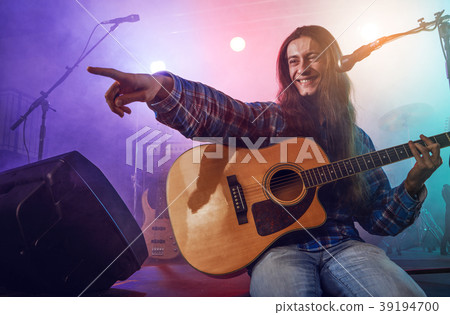 The musician plays an acoustic guitar. Scene The musician plays an acoustic guitar. Scene 39194700